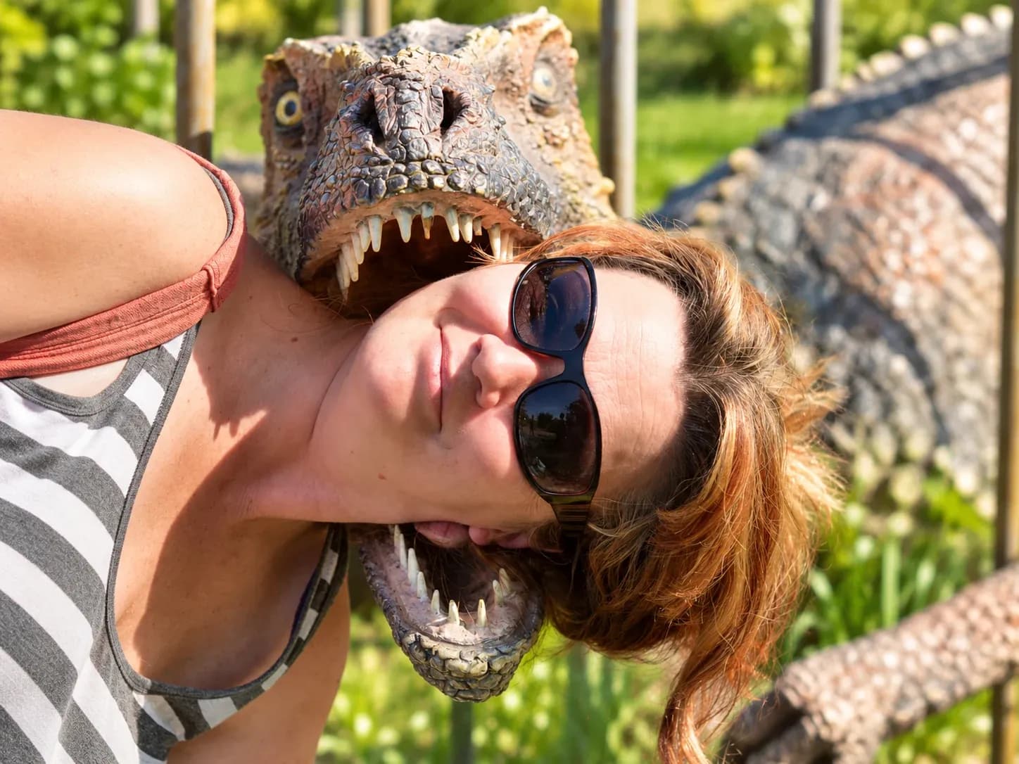Adri v slunečních brýlích se naklání k soše dinosaura.
